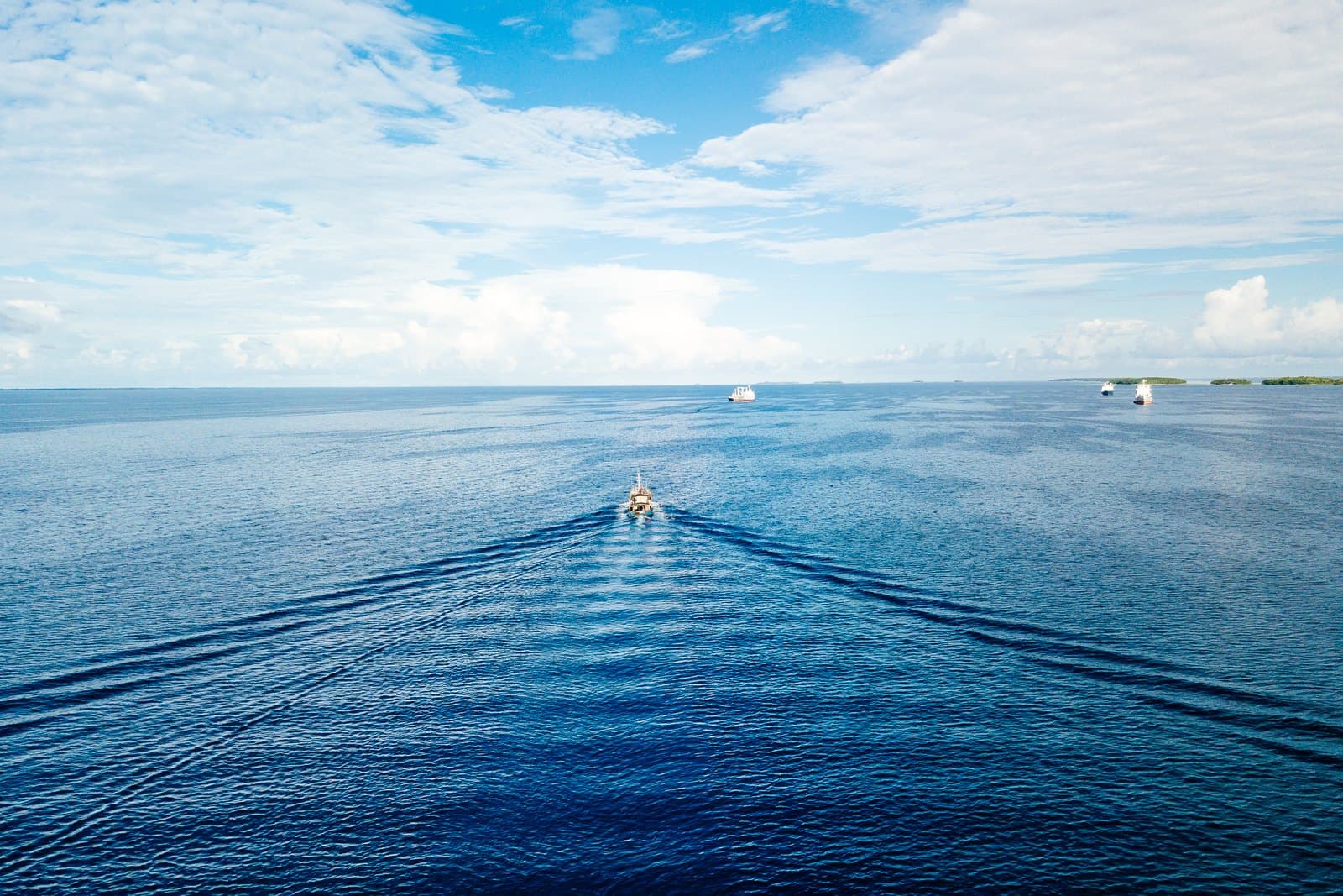 A small fishing boat leaving a wake across a calm tropical sea